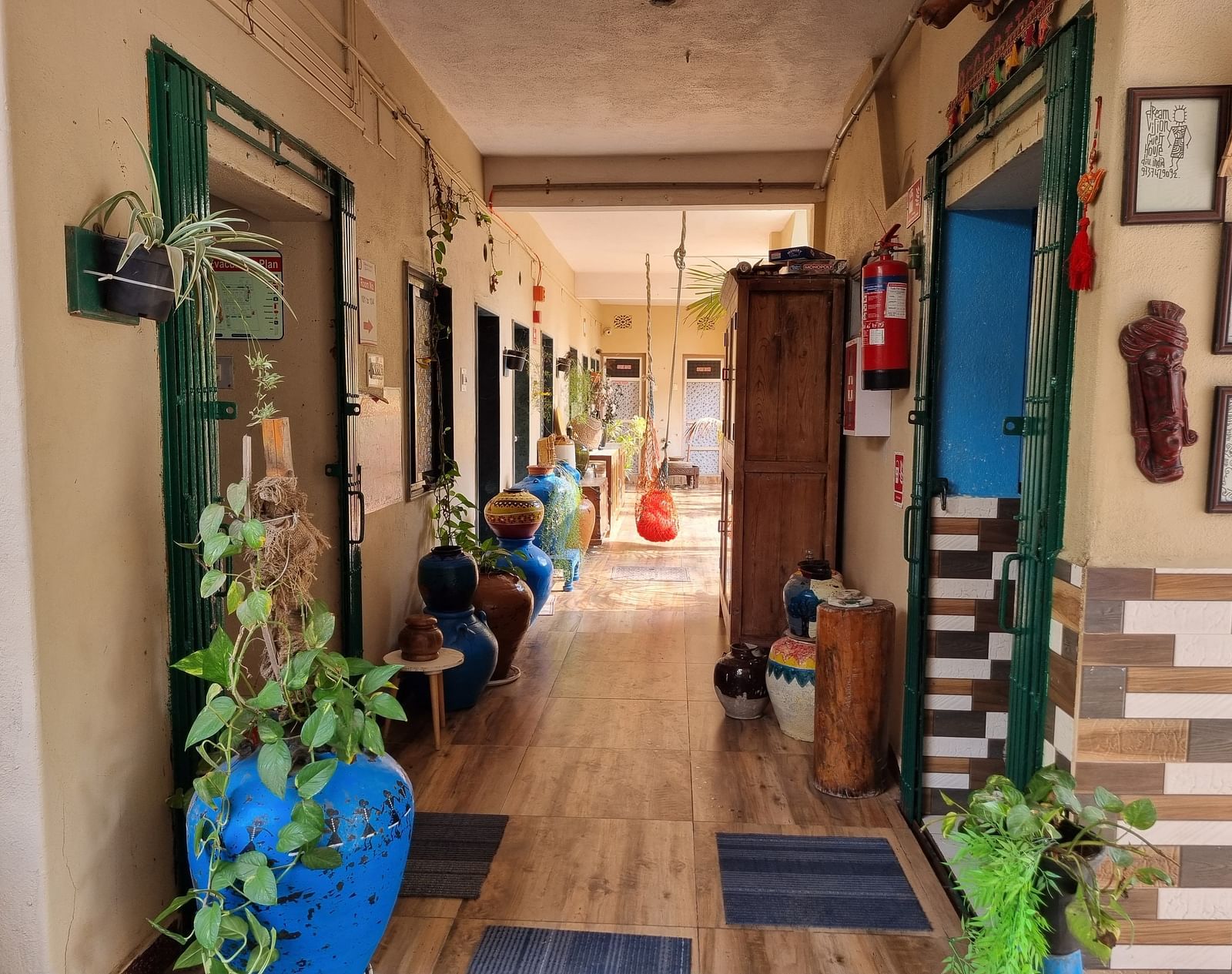 The corridor at the Dream Vision Guest House in Diu surrounded with plants and doors opening to the rooms.