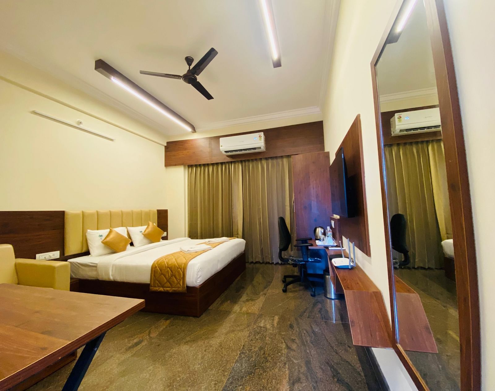 Spacious room with queen bed, wooden interiors, and cosy workspace at Hotel Sahara Tree.