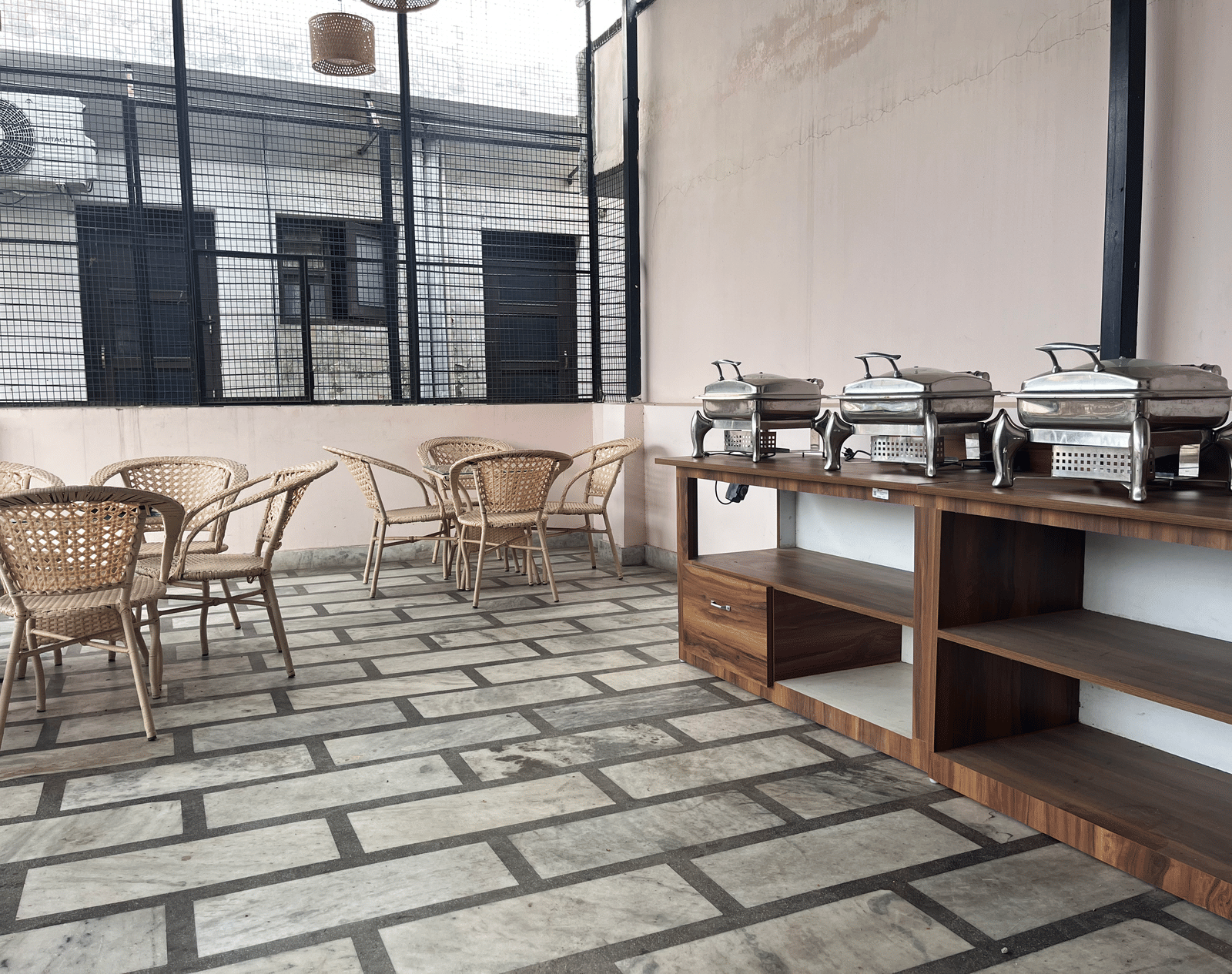A long wooden table in the corner of the dining area featuring several chafing dishes on it at Perfectstayz Value Dhruv Nanda, Haridwar.