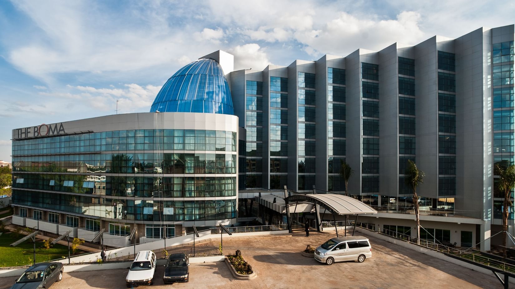 Daytime exterior view of The Boma Nairobi showcasing the building’s glass façade and entrance.