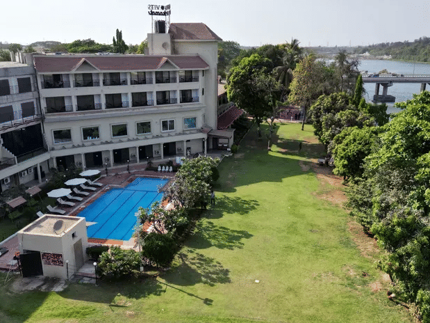 Aerial view of VITS Kamats Resort, Silvassa, showing the main building, lawn, and outdoor swimming pool.