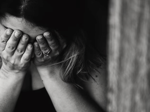 A woman covering her face with her hands, symbolizing stress or anxiety.