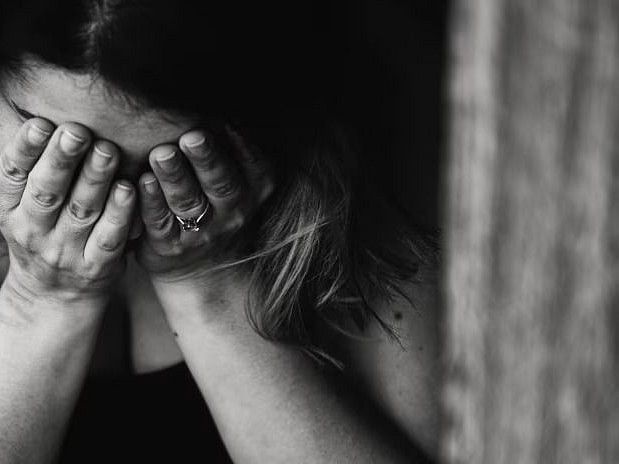 A woman covering her face with her hands, symbolizing stress or anxiety.