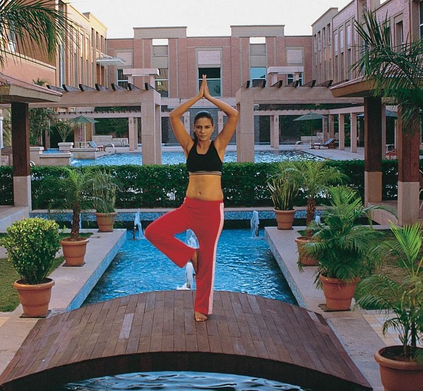 A woman practising yoga on a bridge over a body of water at Nirvana Luxury Hotel, Ludhiana.