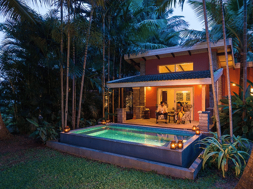 Evening view of The Residence at The Serai Kabini showing a covered patio, seating area, and a private swimming pool surrounded by trees.