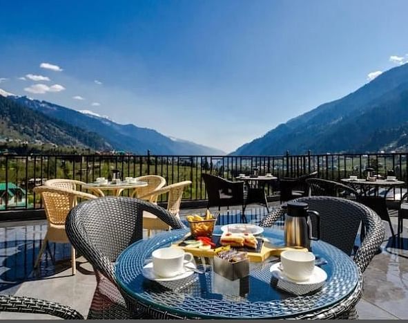 Image of the outdoor seating area at the resort overlooking the hills on a bright day | DLS La Serene Manali