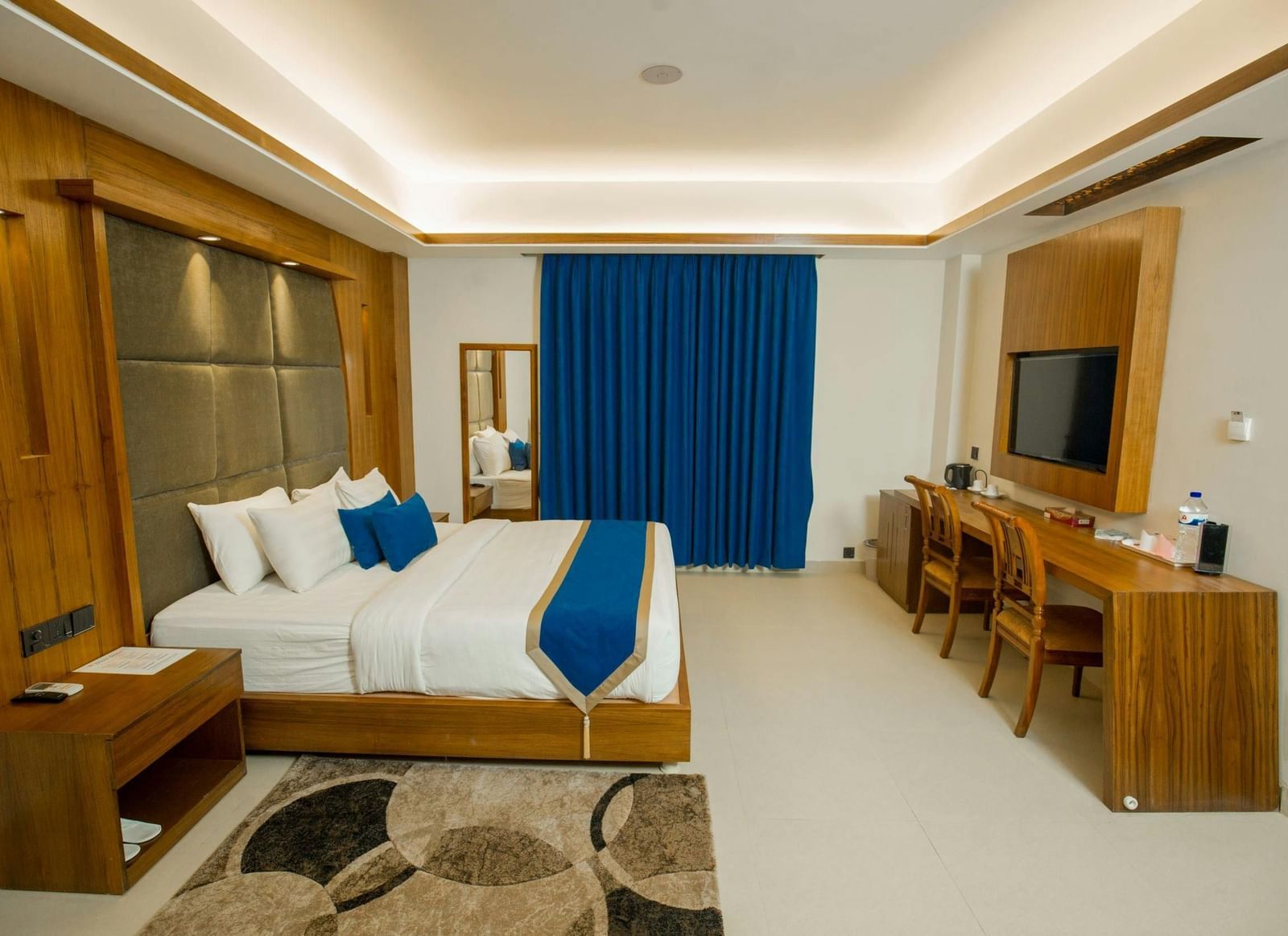 A spacious room featuring a large bed, a practical desk, a cosy seating area, and stylish modern decor