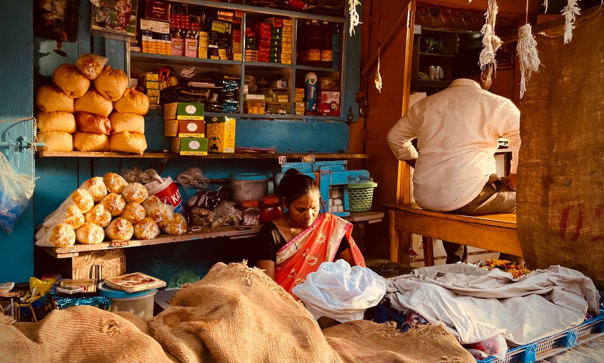 Woman in red sari tending to her small market shop stall.