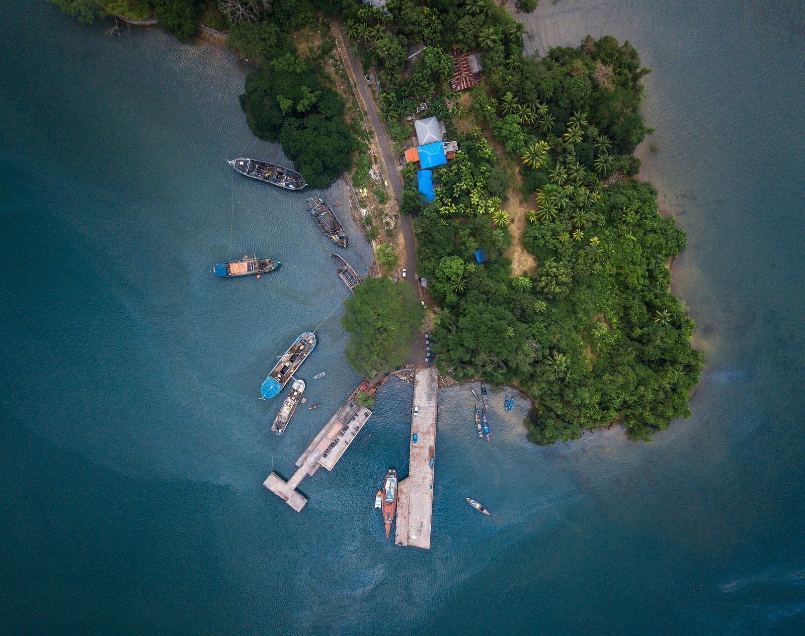 Aerial view of a island with boats docked in clear blue water.