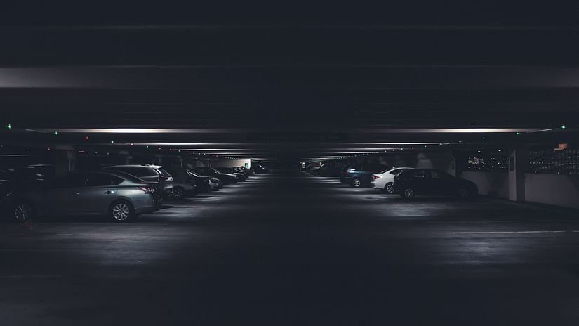 many cars parked inside a parking lot with lights being on where cars are parked below