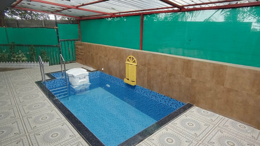 Private outdoor plunge pool area with a wooden privacy fence and tiled deck - DAN Resorts & Weddings, Palghar