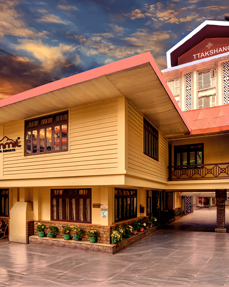 Facade of Summit Ttakshang Residency Hotel & Spa, Gangtok, with a sunset-lit cloudy sky and trees lining the pathway