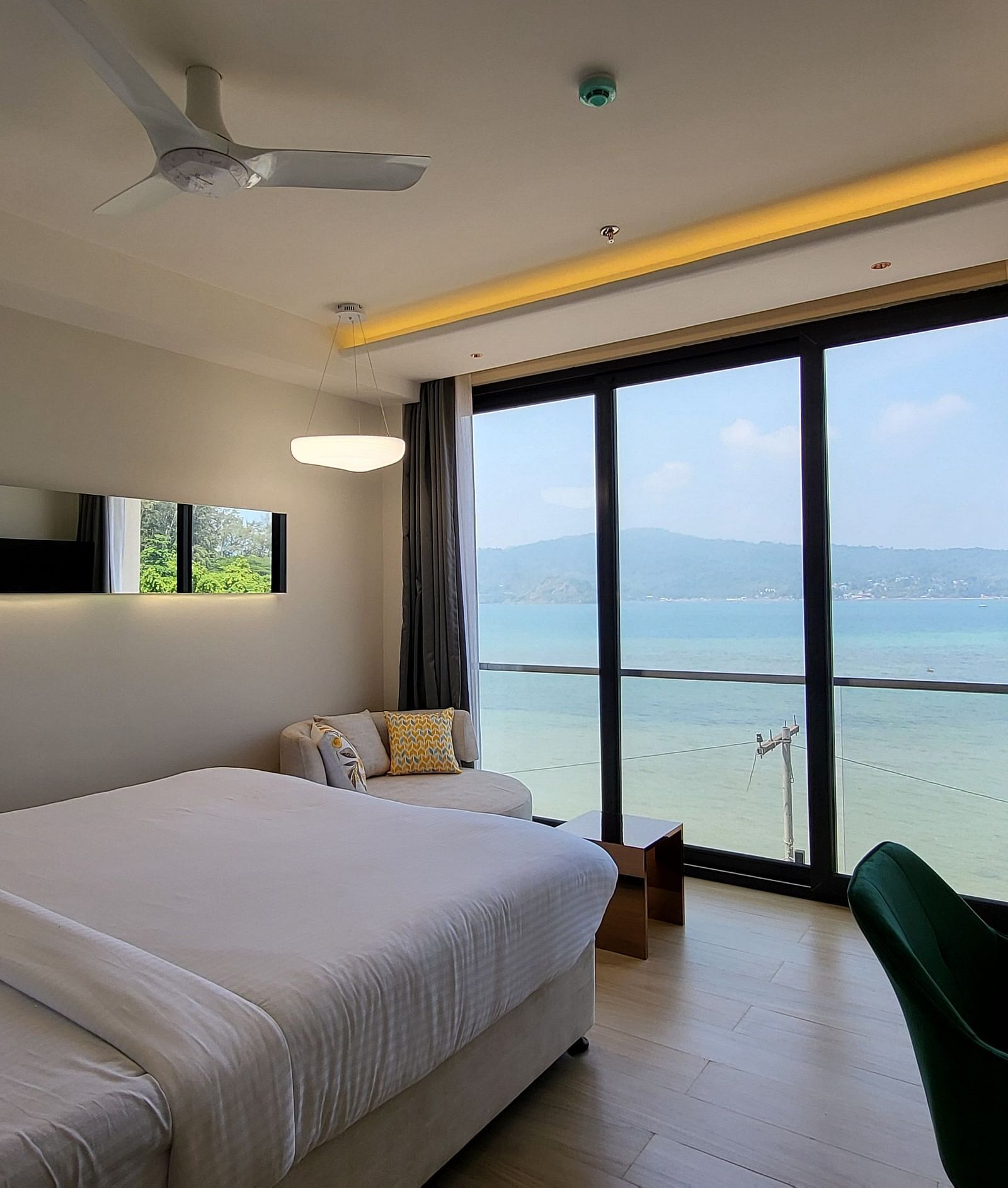 Side view of a single bed facing the ocean with a wall mount TV on the side in the 6ix Sea View Room at 6ix Seashore Hotel, Port Blair