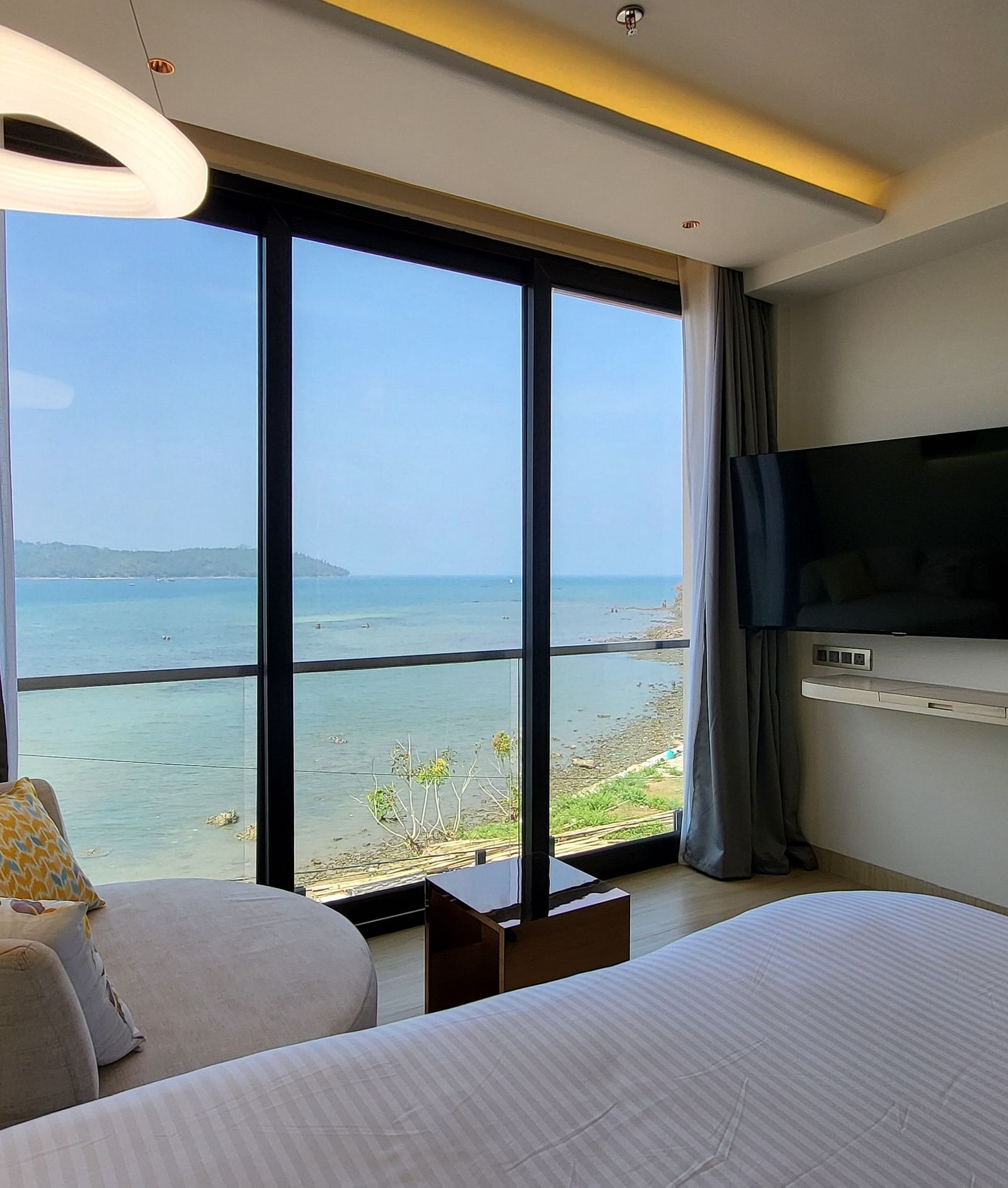 View of half a double bed, a small sofa facing the TV in the 6ix sea view room with Jacuzzi at 6ix Seashore Hotel, Port Blair