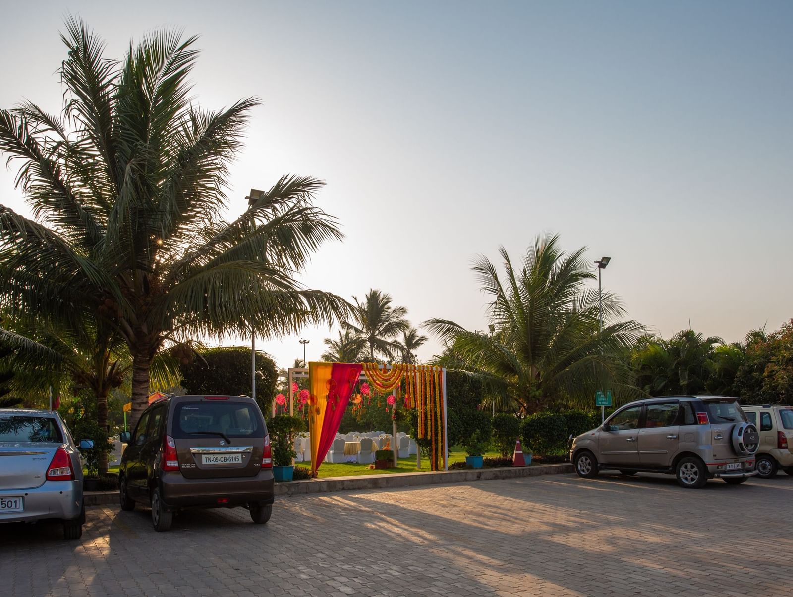 An outdoor parking area at a resort, with several cars parked under palm trees, leading towards a building in the distance  | Citrus Garden | Grand Bay Resort and Spa
