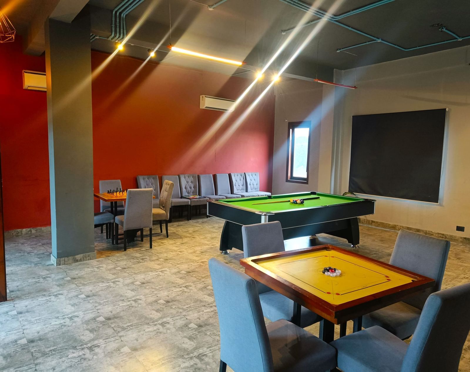 A spacious room featuring a carrom board with chairs around it and a pool table in the background at DLS Forest Vines Resort & Spa, Ramnagar (Jim Corbett).