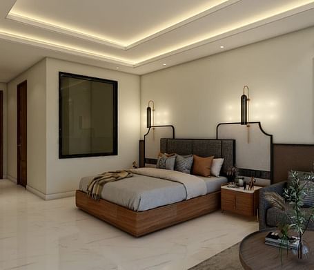 A bedroom with slightly low lighting featuring a double bed with an artistic head board along with a common seating area besides it. - Namaste Corbett