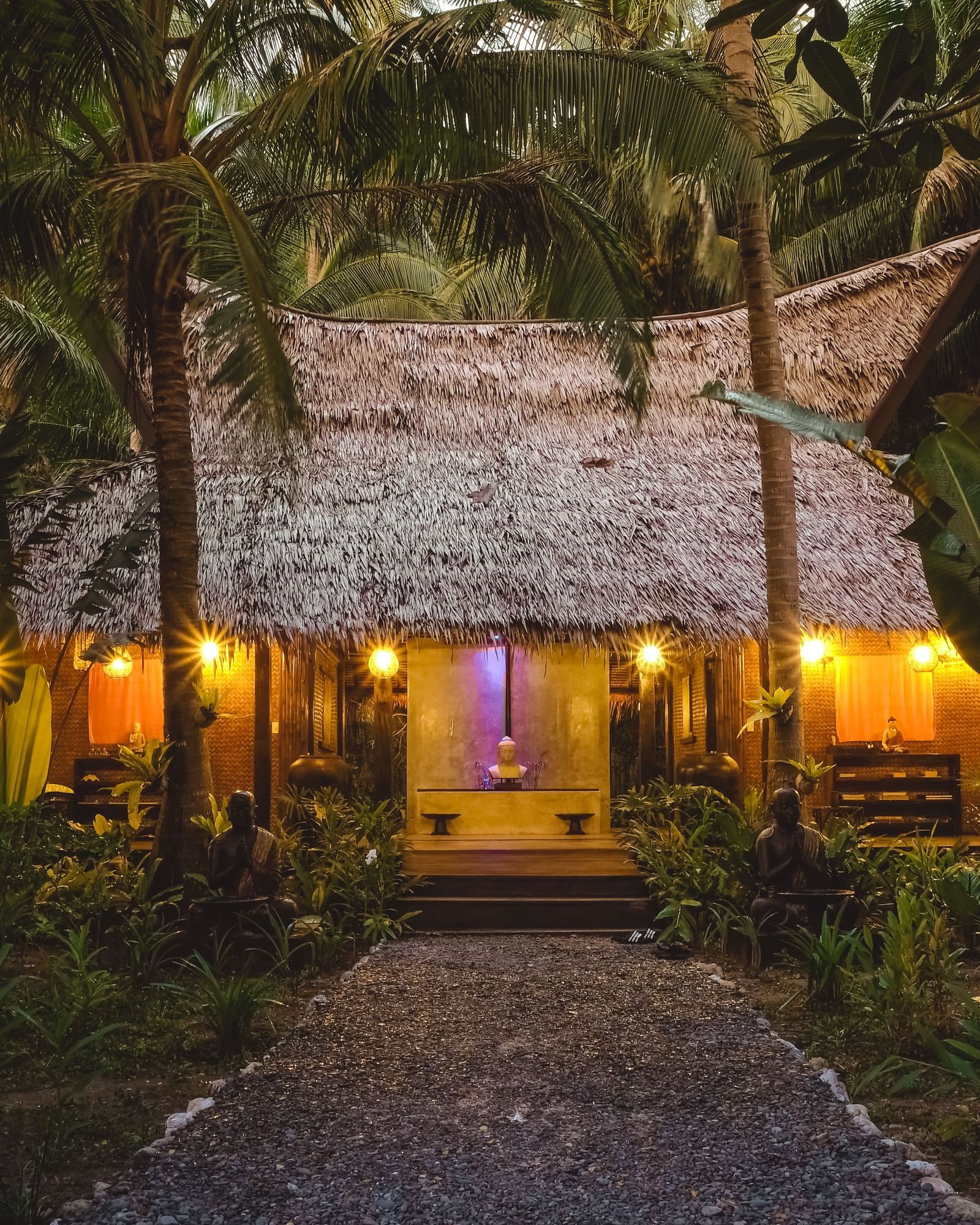 Evening view of a tropical spa hut surrounded by lush greenery and warm lights at Flower Island Resort