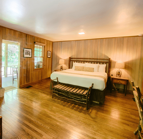 a double bed with two bedside tables with lamps over it placed on either side of it with wooden interiors - Historic Tapoco Lodge