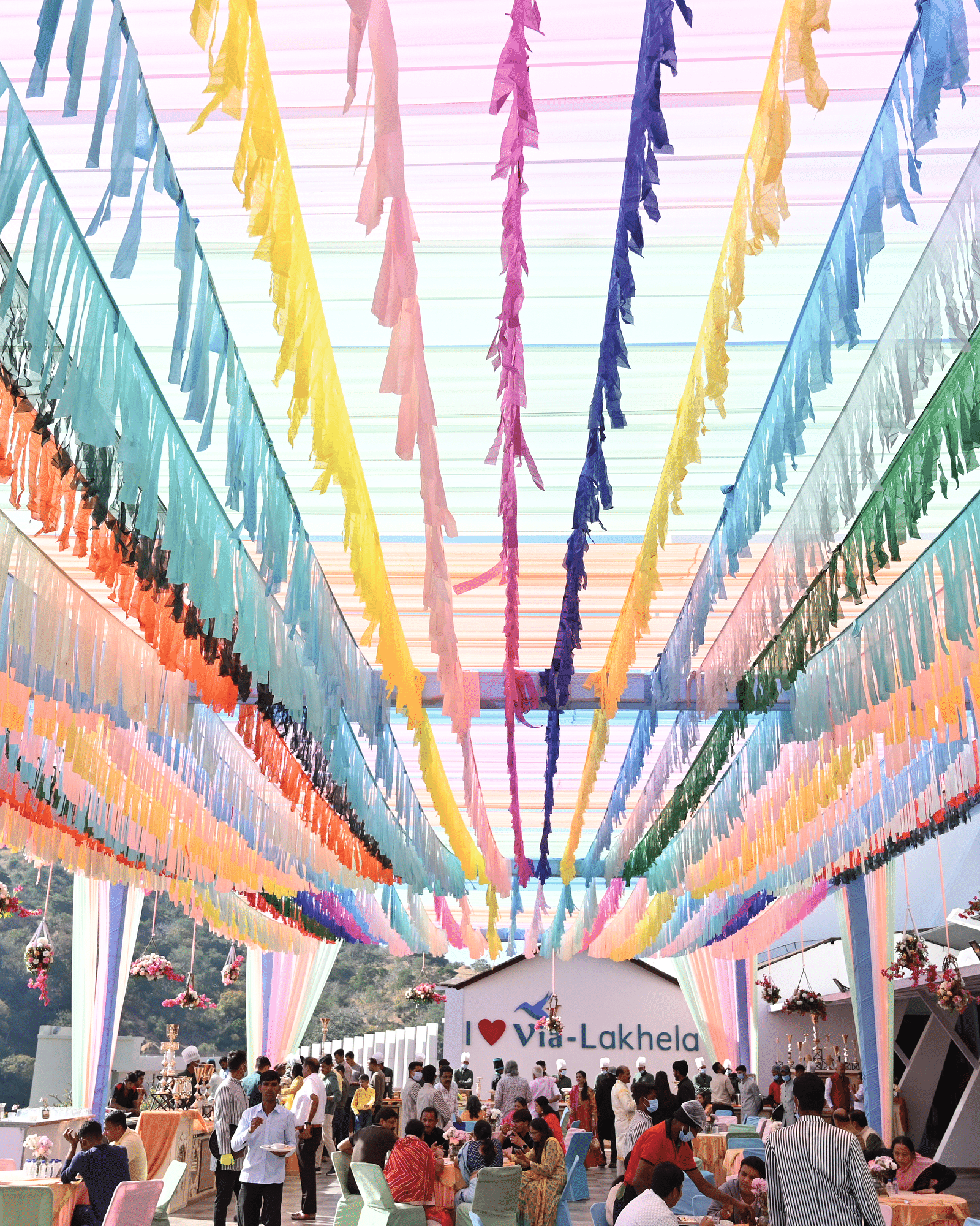 Colourful ribbons strung overhead with people gathered below - Via Lakhela Resort & Spa