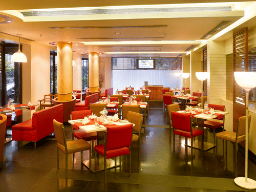 The interior view of the dining section featuring 4-chair seating in the centre and sofa seating on the sides at Aromas Coffee Shop inside Kenilworth Hotel - a hotel near City Centre 2, Kolkata.