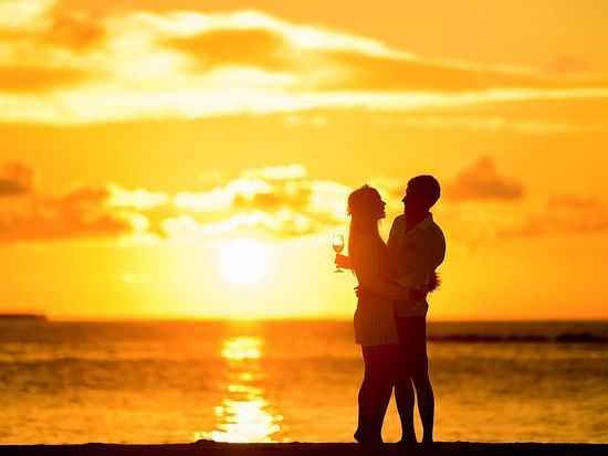 alt-text Silhouette of couple holding each other on a beach during sunset