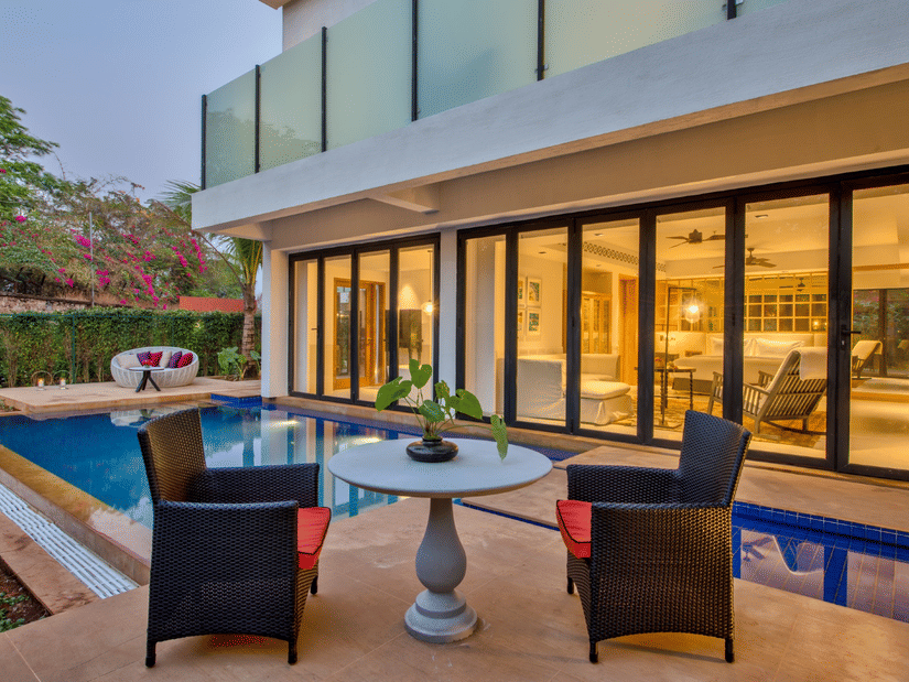 A view of the sit out area near the private pool of an Azaya XL Pool Suite with ceiling to floor windows on the building next to the pool at Azaya Beach Resort, Goa, A South Goa stay near the beach.
