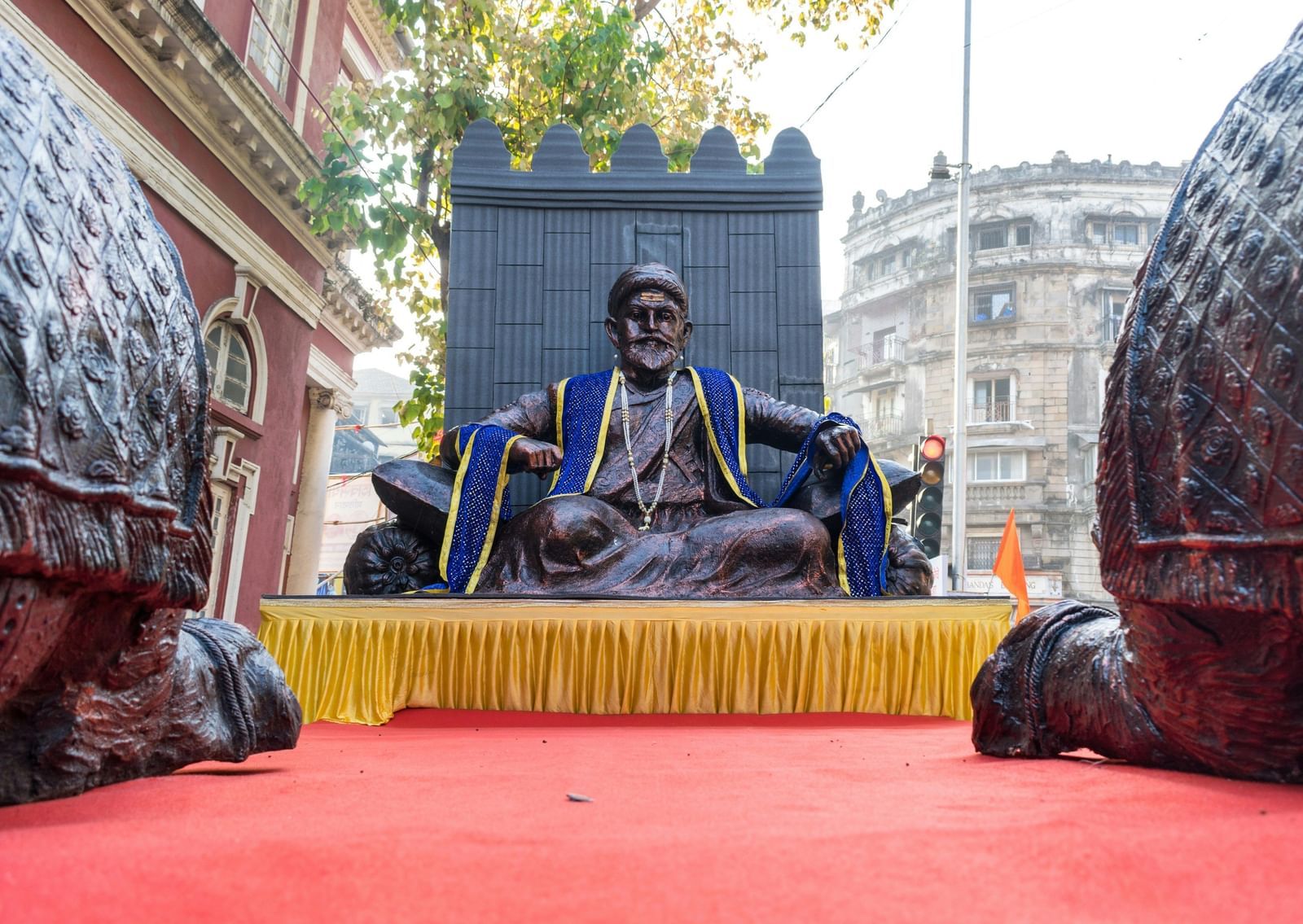 A view of Shivaji Maharaj's idol in a sitting position on a stage with a garland over the idol during Shivaji Maharaj Jayanti