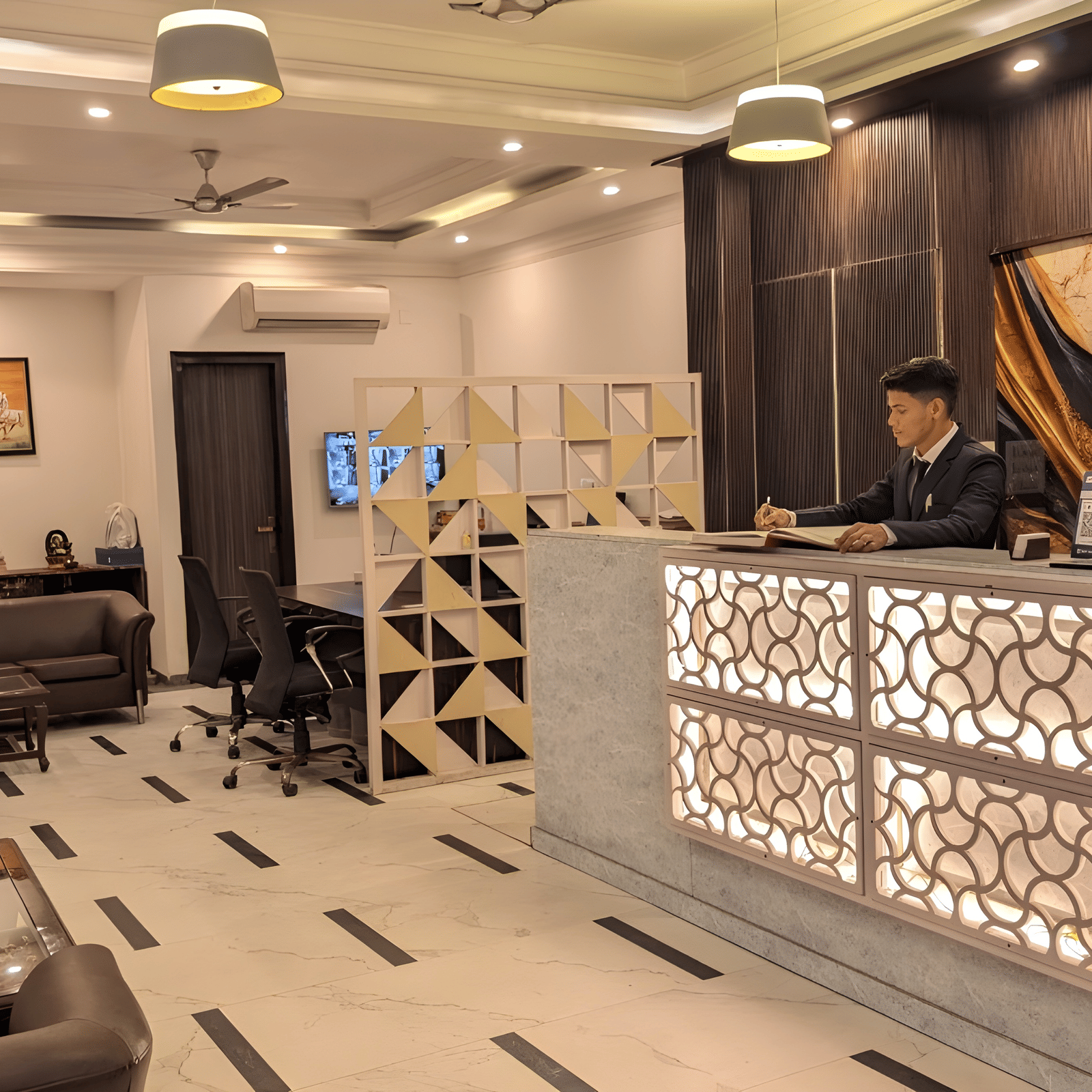 The bright entrance lobby of Hotel Apple Park Delhi, showing the reception desk in the distance, polished white floors with black accents, and tan seating.
