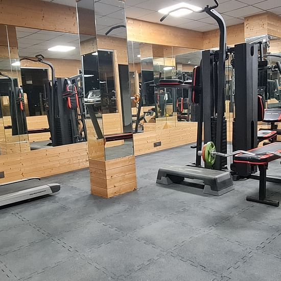 Well-equipped gym at Shaheen Bagh showcasing strength training stations and a reflective interior.