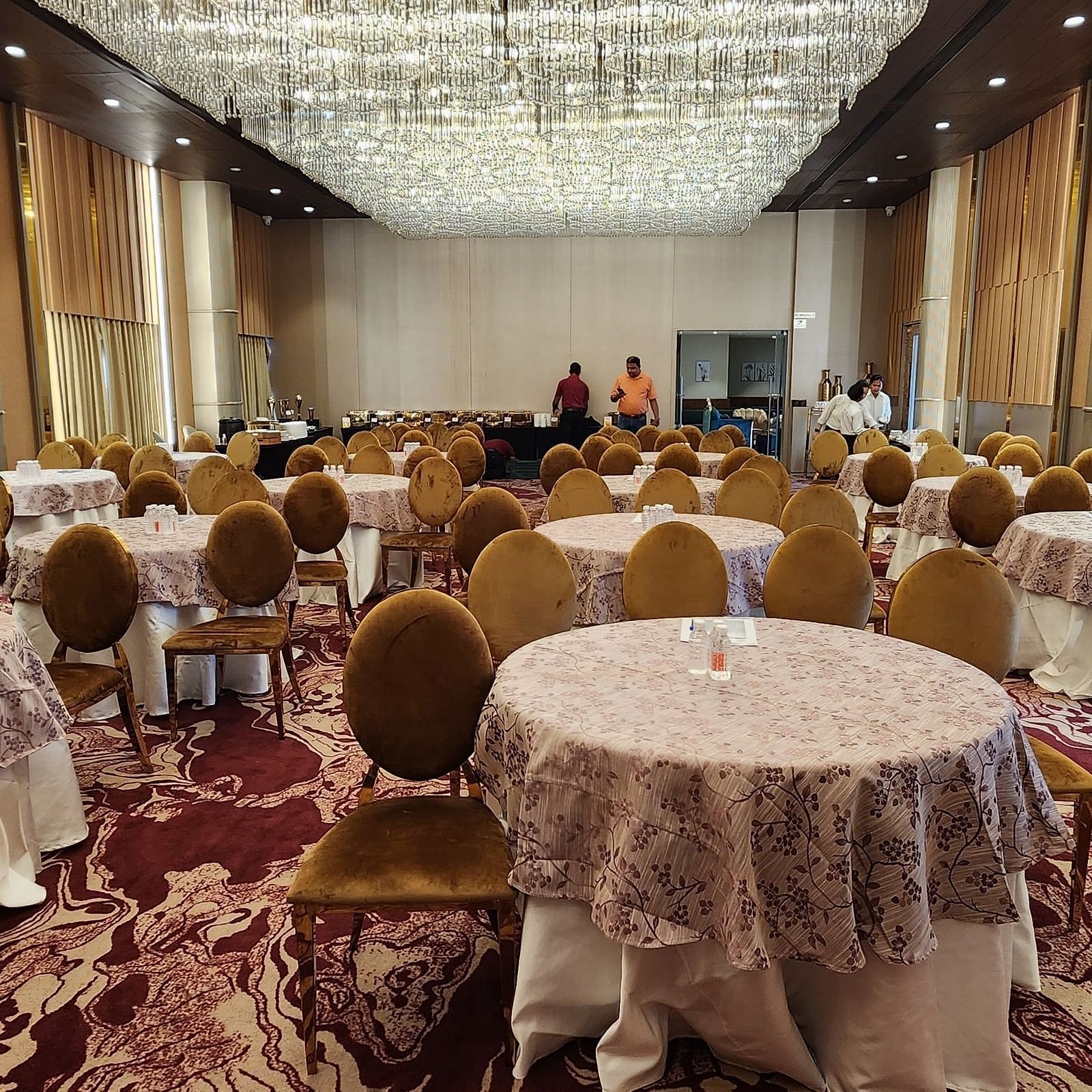 a banquet hall in Lords Inn Rajkot with cluster seating arrangement and a buffet counter at the back