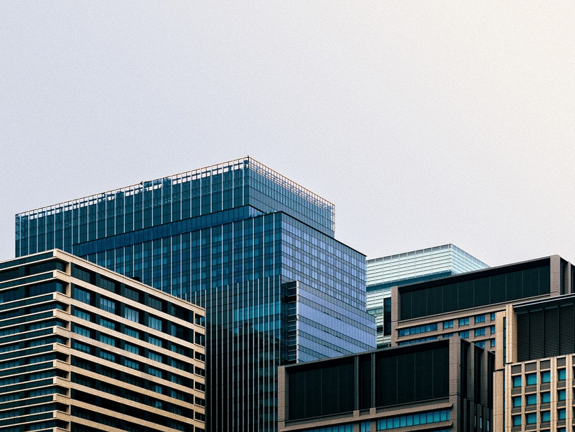 A cluster of modern multi-story office buildings with glass and textured facades against a pale sky.