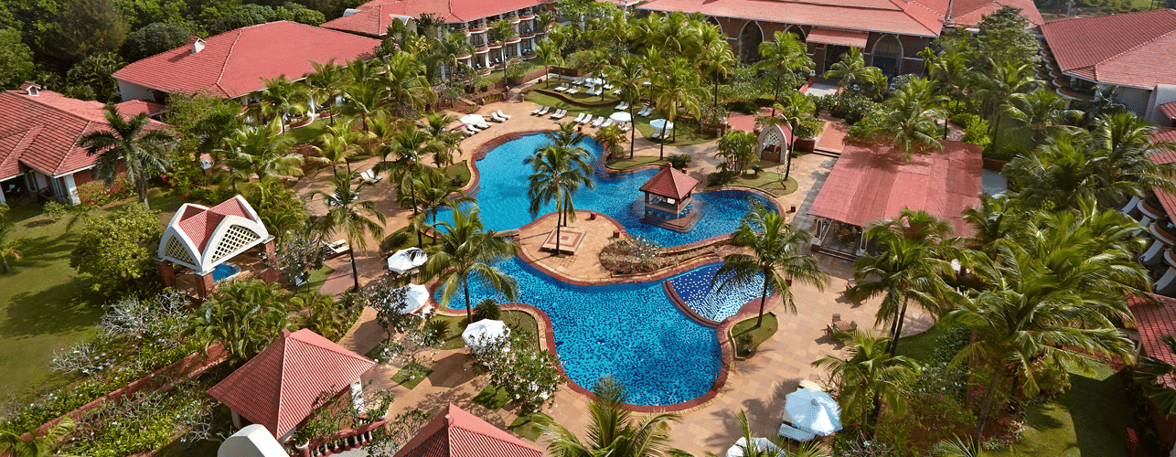Aerial view of the Caravela Beach Resort property and pool with tree covering.