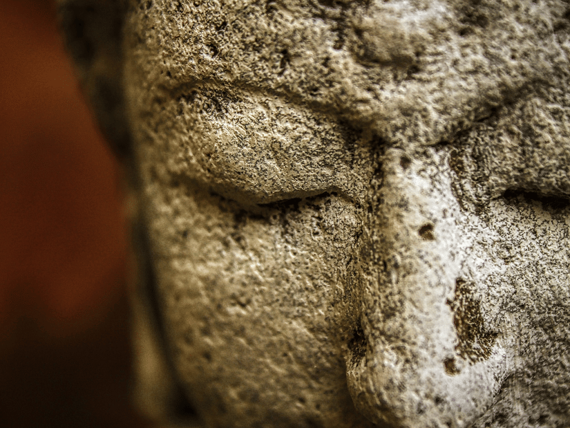 A close-up profile view of a stone statue of a face with closed eyes | HHI Varanasi