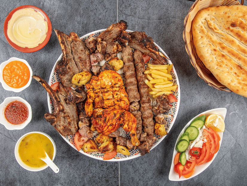 A mix grilled kebab platter with different sauces on the side