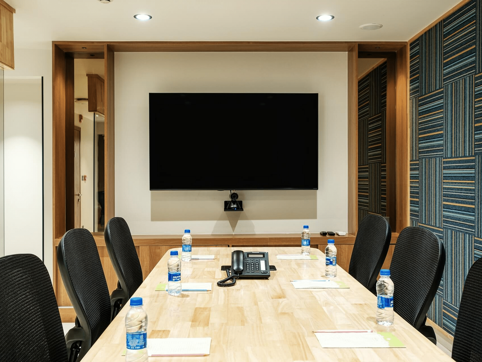 View of the full boardroom at Indie Stays, Jaipur, with chairs lined along the sides and a screen at the front.