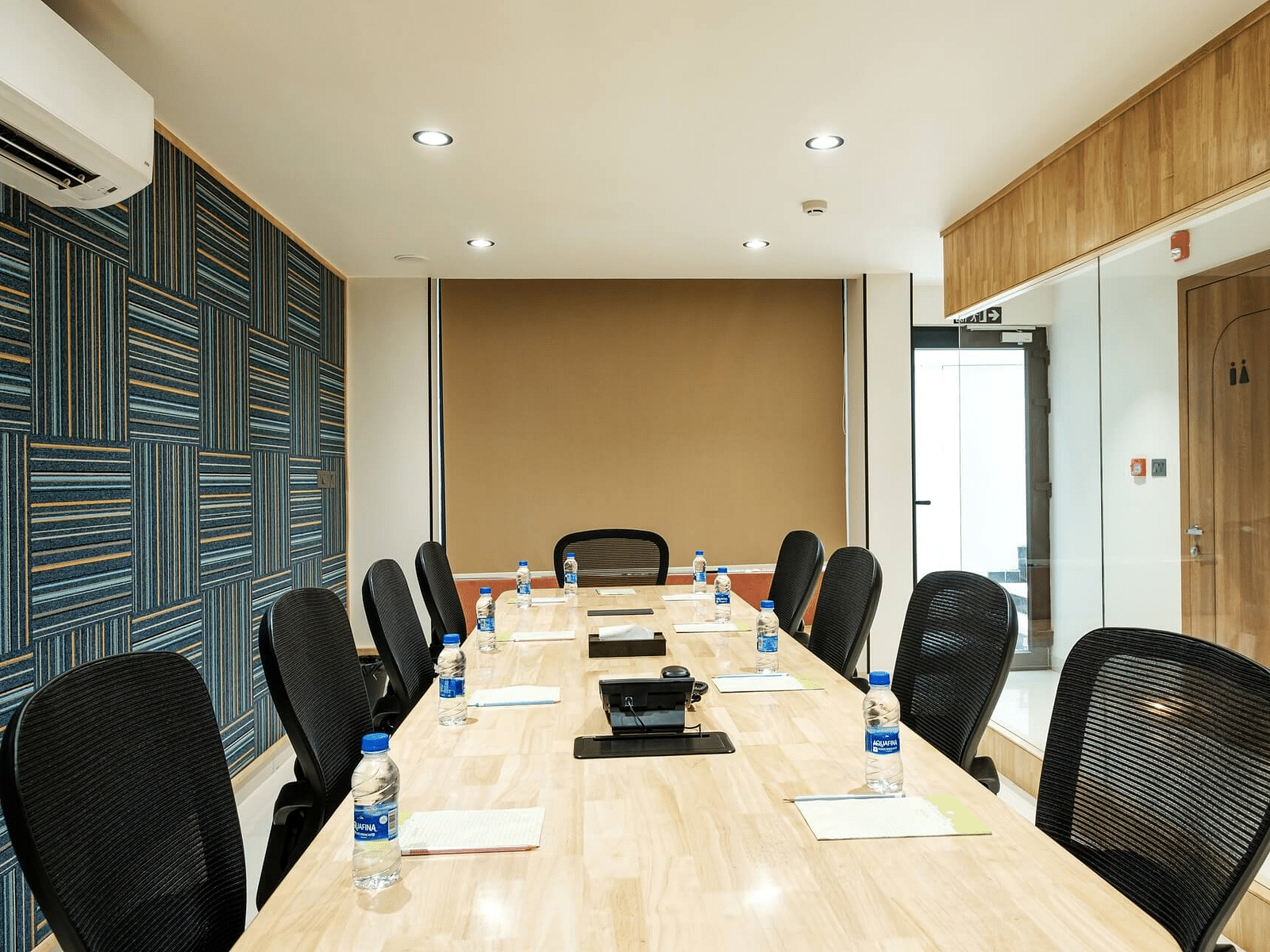 View of the full boardroom at Indie Stays, Jaipur, from the front, with chairs arranged along the sides and a wall-mounted AC.