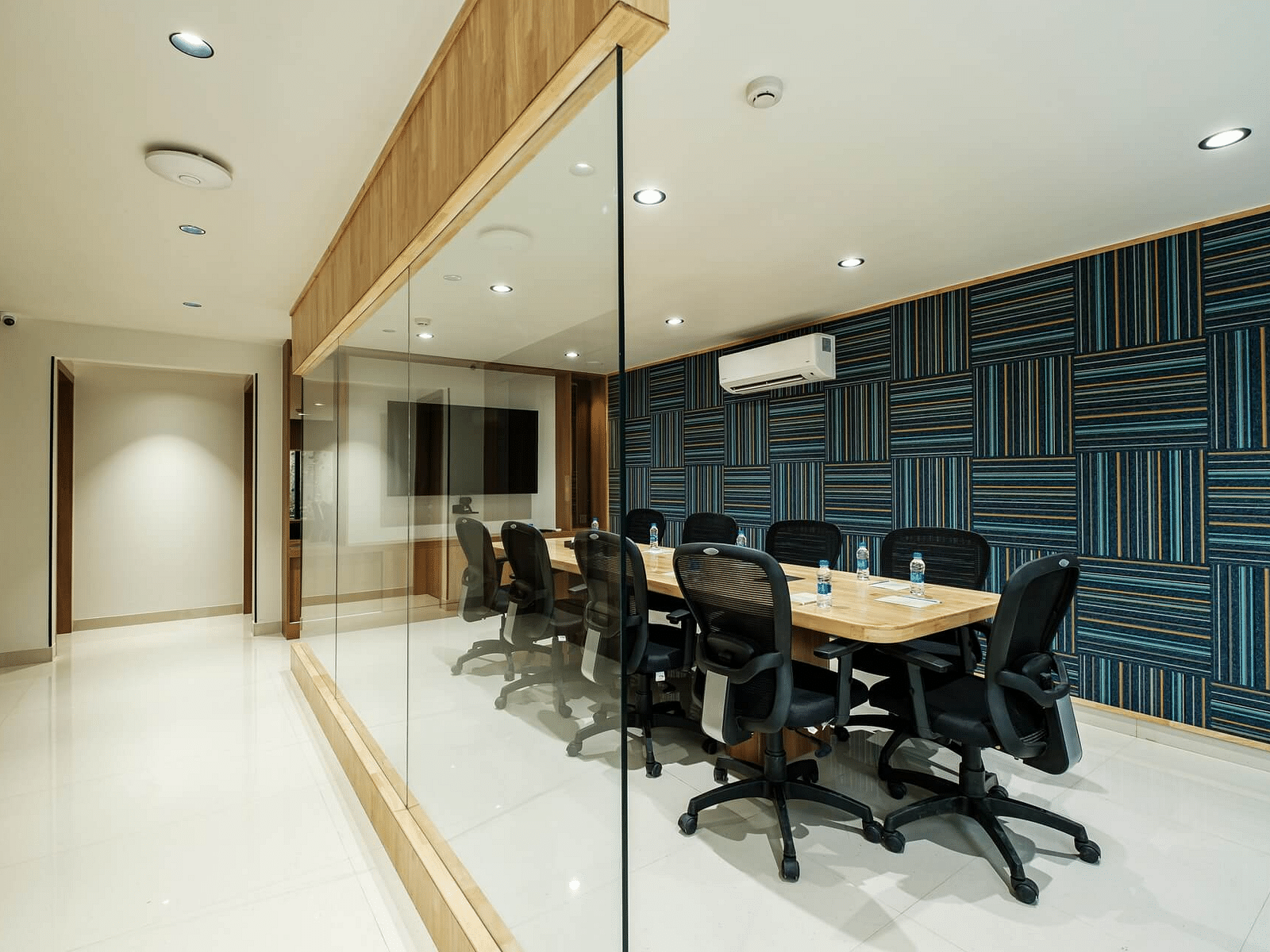 Conference room at Indie Stays, Jaipur, with a rectangular table and chairs arranged around it, visible through a glass partition.