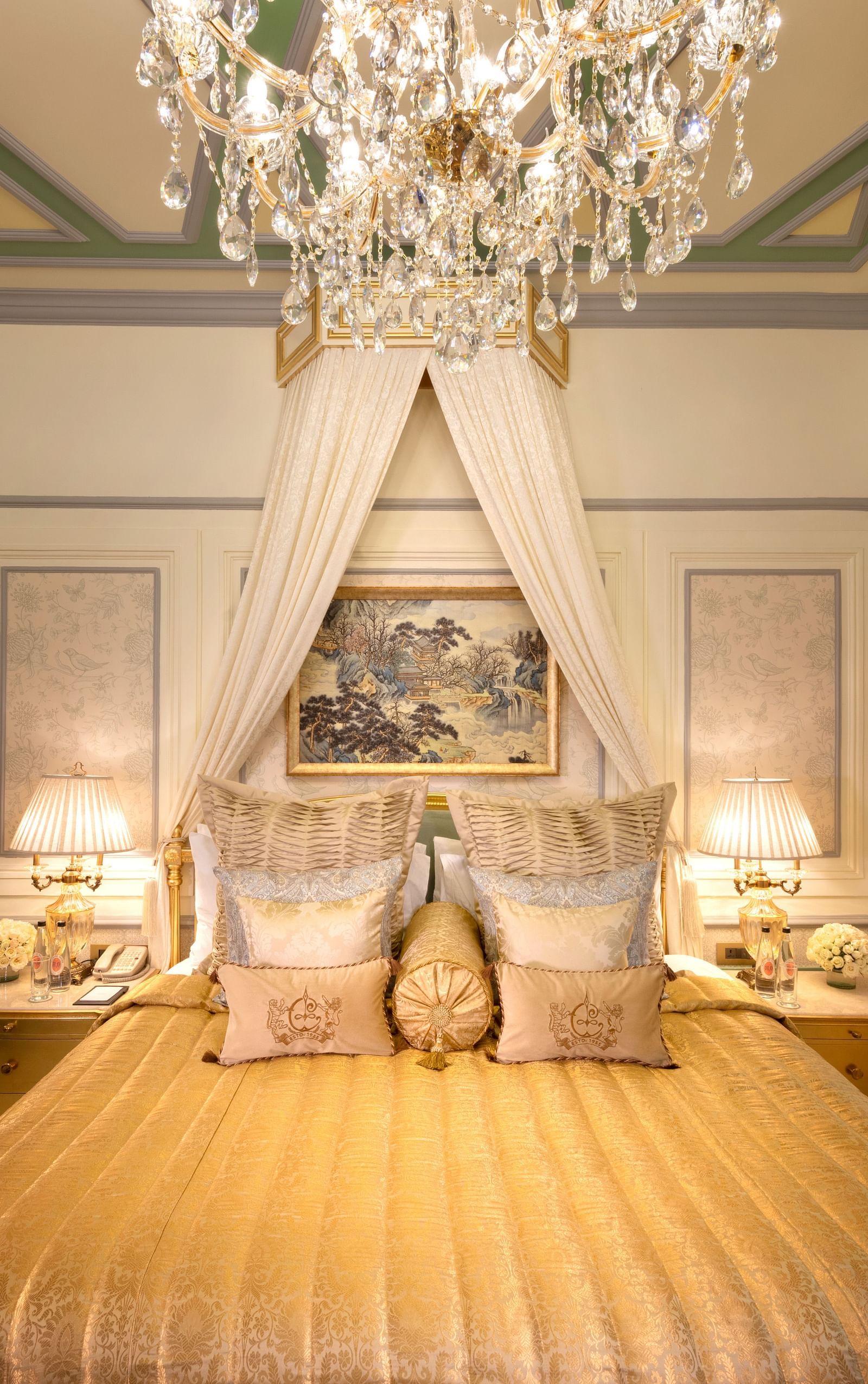 image of a luxurious bedroom with a golden comforter spread across the bed with well set pillows and cushions - The Claridges New Delhi 
