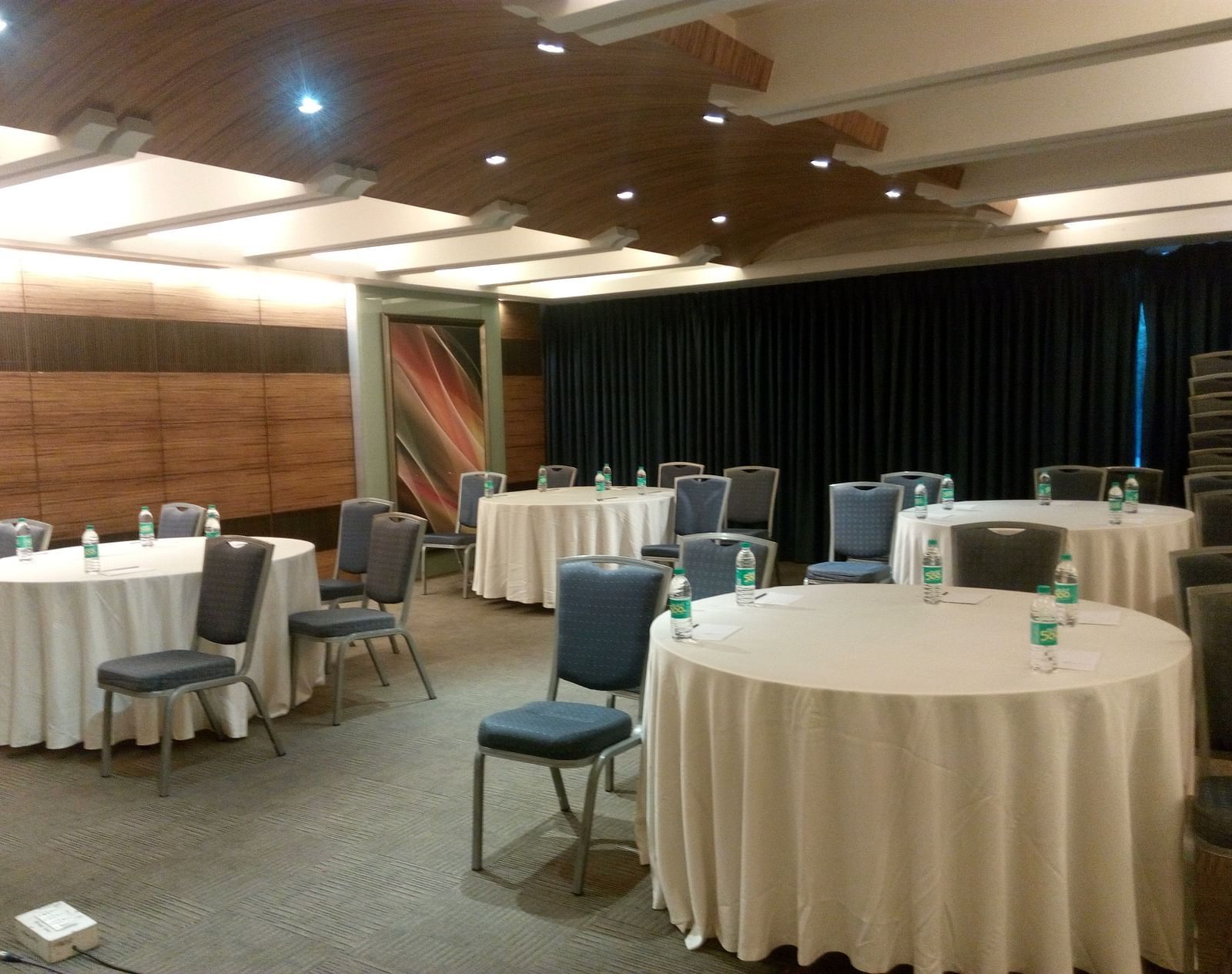 Shot of a meeting hall featuring round tables and black chairs | Mirage Hotel