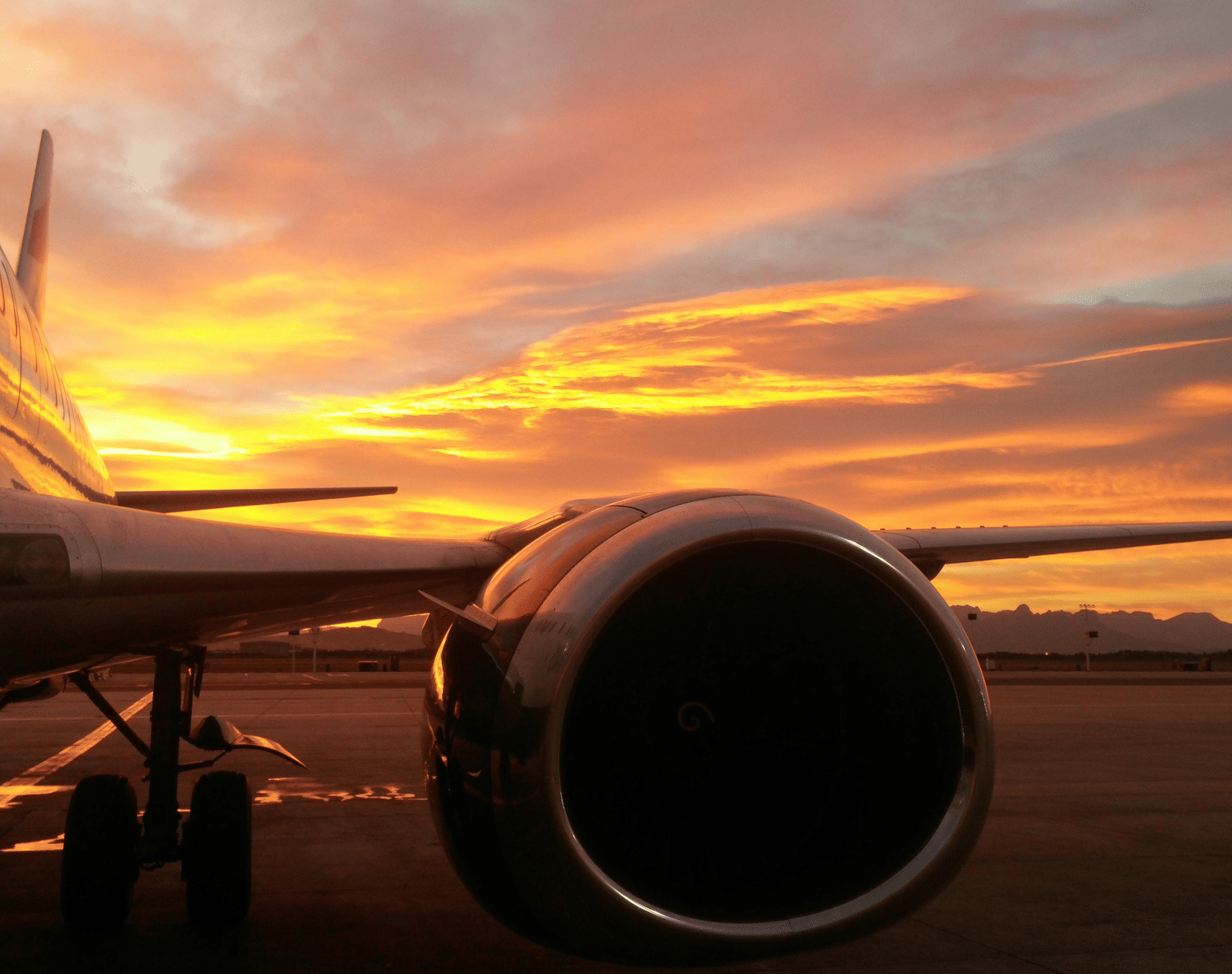 An airplane parked on a runway at sunset.