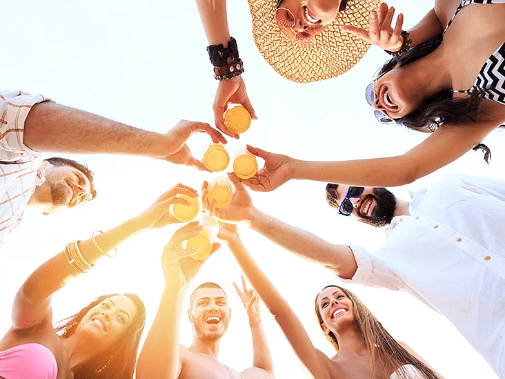 A low-angle view of a group of friends raising their glasses in a celebratory toast - S Hotel Kingston, Jamaica