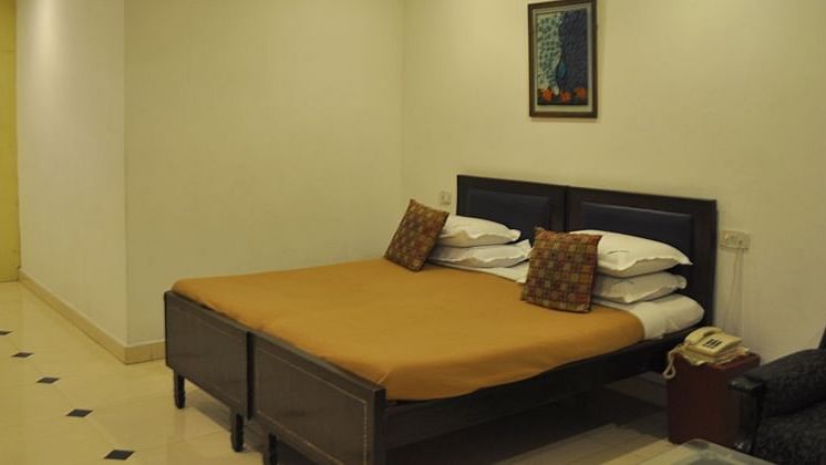 Spacious hotel room with ambient lighting, a large bed, and seating area with one chair