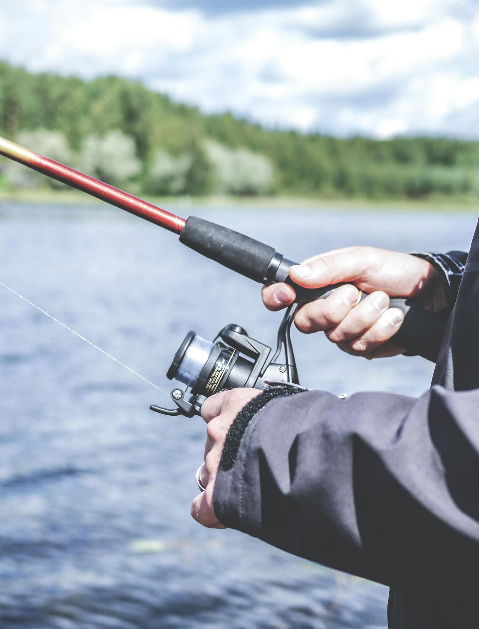 A close up shot of a person reeling in their catch at a lake.