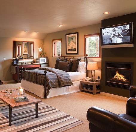 Meadowview Suite featuring a couch, a teapoy, a plush bed, a wall-mounted television and a leather couch - Brewery Gulch Inn & Spa