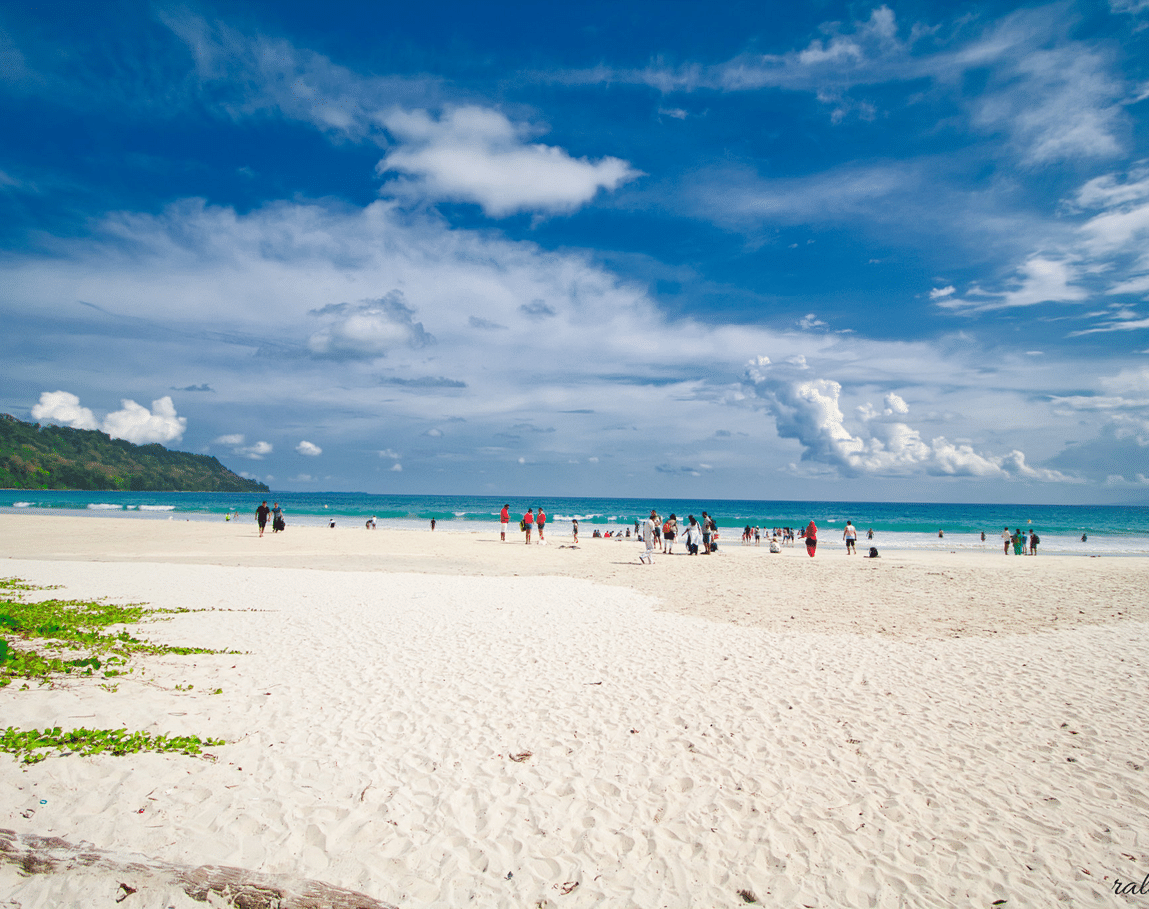 A wide angle shot of the Radhanagar Beach with a white sands coastline in the foreground.