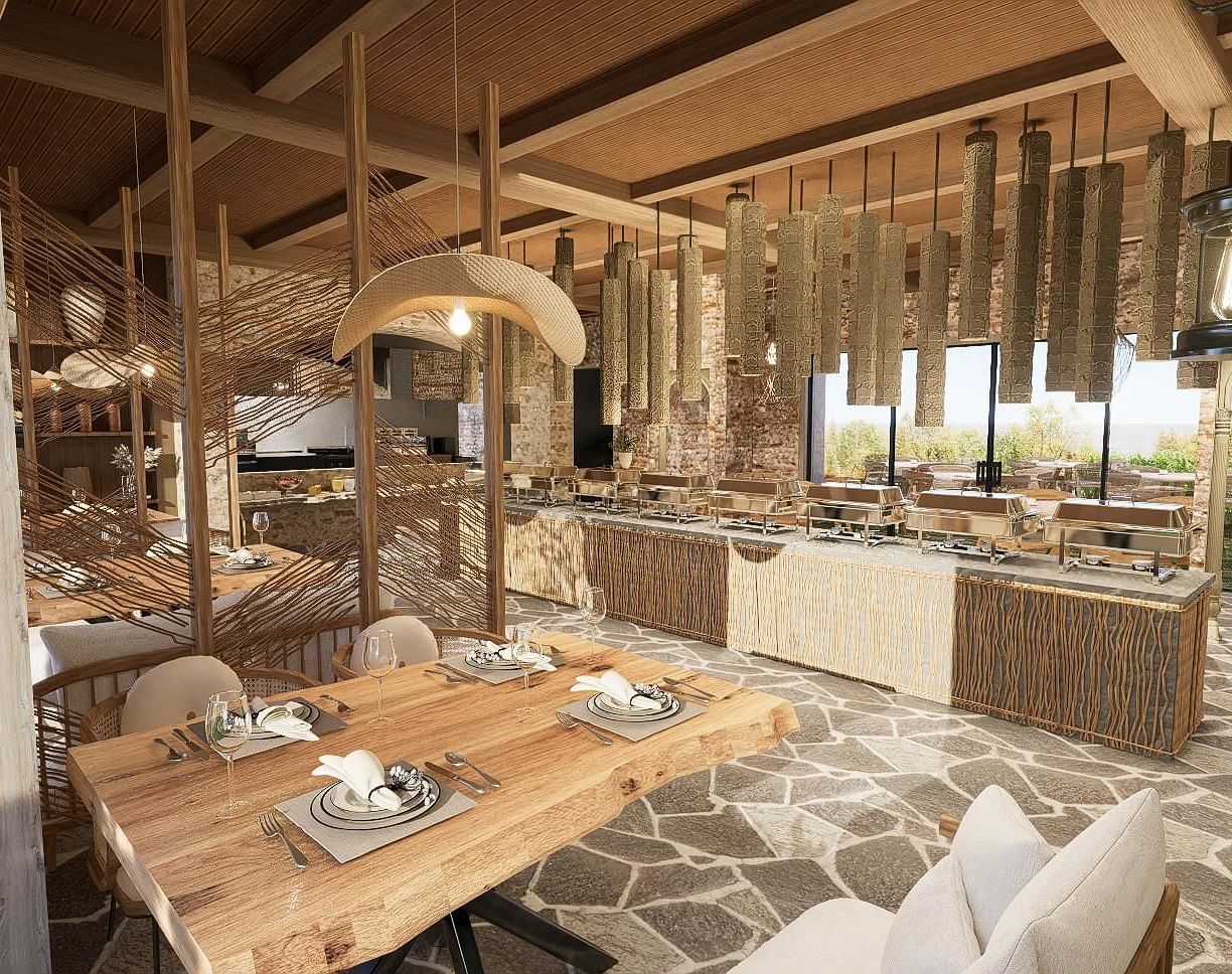 Diagonal view of the restaurant with neatly set tables and chairs, featuring a central table with a buffet setup at The Evren, Vagator.