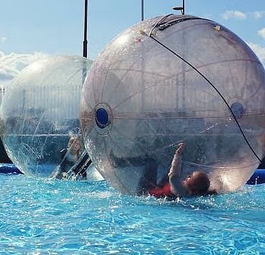 Two huge inflated balloons floating in the swimming pool on a bright sunny day.