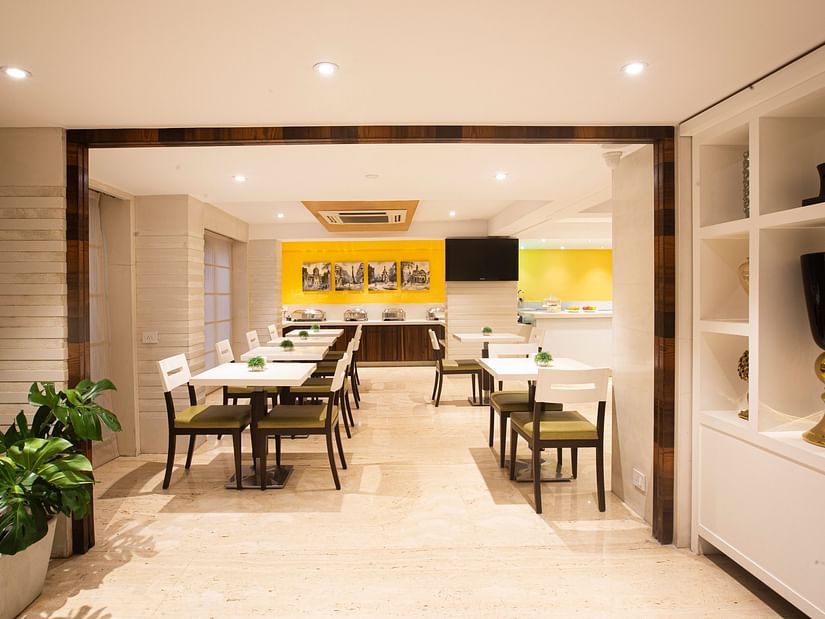 A wide-angle view of a dining area featuring a flat-screen TV on the wall, with neatly arranged tables and chairs, creating an inviting atmosphere.