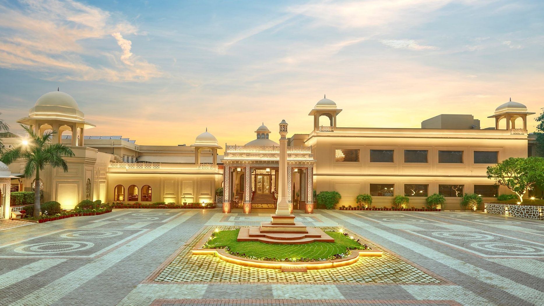 Grand view of a palatial building with domes and a large courtyard at sunset - Heritage Village Resorts & Spa.